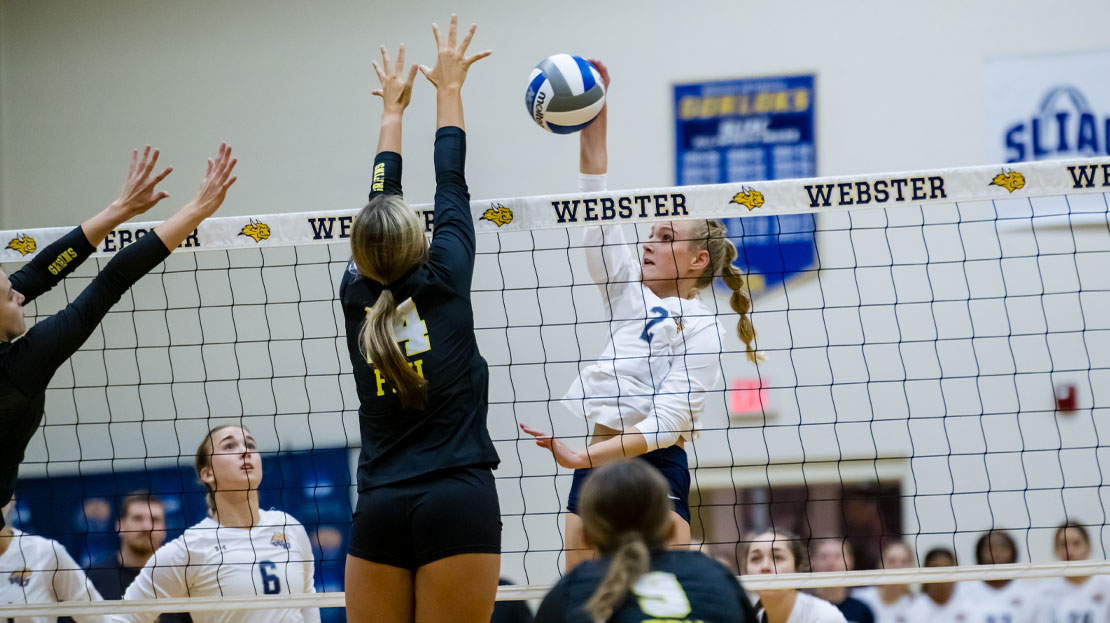 A Webster volleyball player jumps to spike the ball.